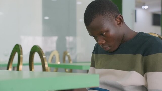 Concerned individual composing verse in cafe. Isolated figure in striped sweater crafting poem with anticipation. Anxious student poet in green setting readsies poem at cozy cafe table
