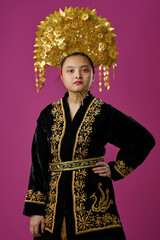 Naklejka premium Portrait Of Young Indonesian Asian Woman Wearing Traditional Gold Headdress And Embroidered Black Robe