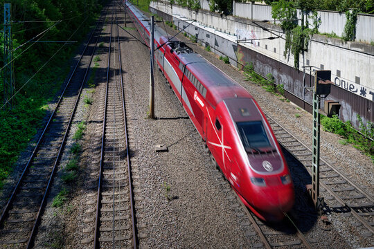 Cologne, Germany April 29 2026: A red Eurostar (formerly Thalys) high-speed train moving on tracks. Elevated view of European railway tracks on a sunny day with motion blur.