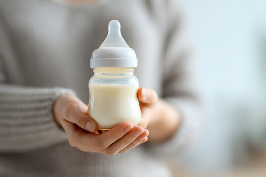 Woman hand holding a baby bottle of milk