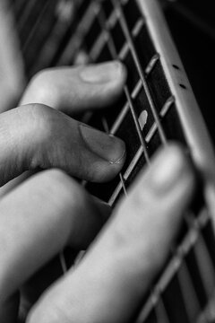Woman playing acoustic classical guitar. Extreme closeup of musician fingers pressing strings on fretboard. Vintage black and white photography with noise and analog film grain style