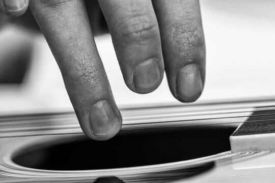 Musician touching guitar string. Closeup of woman fingers playing acoustic instrument. Black and white retro style musical performance, chord practice and creative hobby concept. Grainy texture effect