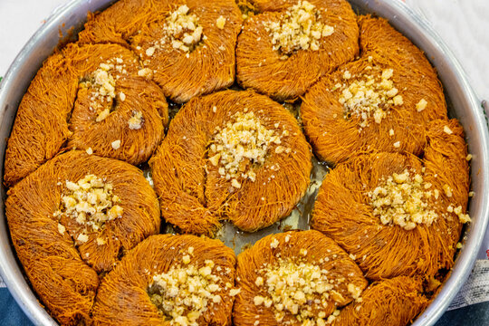 Turkish traditional dessert in various flavors. Pieces of turkish traditional declious dessert pohlava with nuts and honey. Turkish sweets. Turkish Burma Kadayif with Pistachio Powder in Tray Dessert 