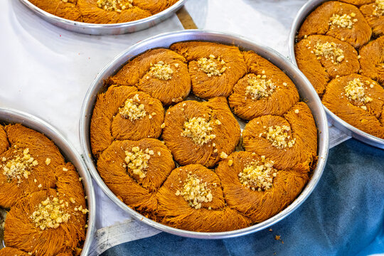 Turkish traditional dessert in various flavors. Pieces of turkish traditional declious dessert pohlava with nuts and honey. Turkish sweets. Turkish Burma Kadayif with Pistachio Powder in Tray Dessert 