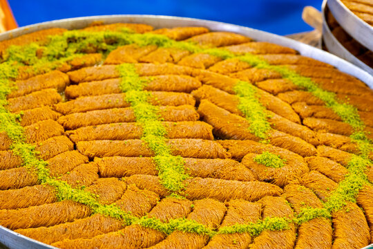 Turkish traditional dessert in various flavors. Pieces of turkish traditional declious dessert pohlava with nuts and honey. Turkish sweets. Turkish Burma Kadayif with Pistachio Powder in Tray Dessert 