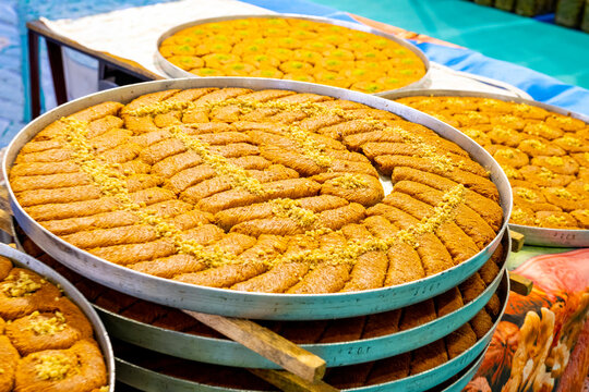 Turkish traditional dessert in various flavors. Pieces of turkish traditional declious dessert pohlava with nuts and honey. Turkish sweets. Turkish Burma Kadayif with Pistachio Powder in Tray Dessert 