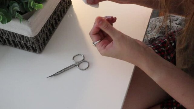 Woman removing nail polish at home with cotton pad at table. Personal beauty routine for manicure care, hand grooming, self care and domestic lifestyle concept.