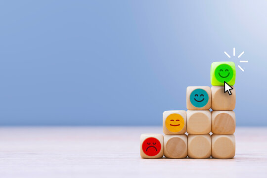Pyramid of wooden cubes from red to green smiley face clicked by cursor. Concept for service quality, business success, customer experience and career growth. Dissatisfied to a happy face being.