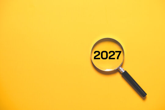 New Year 2027 concept with magnifying glass and 2027 on yellow background, representing future goals, planning, vision, business strategy, fresh start, opportunity and success in the upcoming year