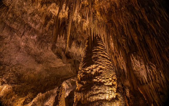 Golden glow illuminates ancient limestone stalactites inside the cave.