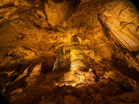Illuminated stalactites glow in a vast cave.