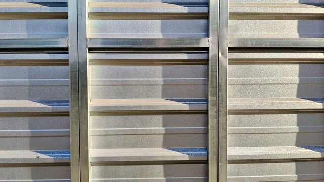 Close-up of a corrugated galvanized metal sheet with a textured surface and horizontal lines, ideal for modern architectural or industrial backgrounds.