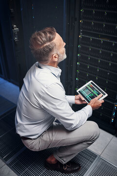 Tablet, man and engineer with inspection, update or programming on app in data center. Cybersecurity, database and mature technician in server room with network maintenance or code for software