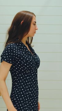 Fashion fit investigation. Individual examines polka dot attire while adjusting neckline attentively. Person carefully scrutinizes fit of polka dotted outfit and alters neckline accordingly