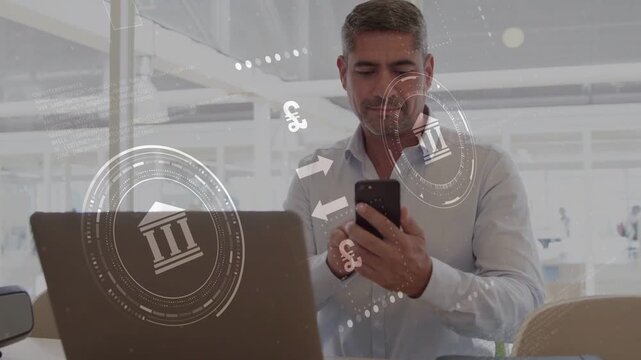 Mature man tapping smartphone behind laptop activating banking HUD $&euro;&pound;&yen; icons  and  confirming payme