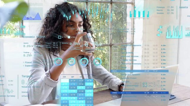 Woman focusing on laptop and reviewing animated tech charts, pausing to sip mug, resuming typing