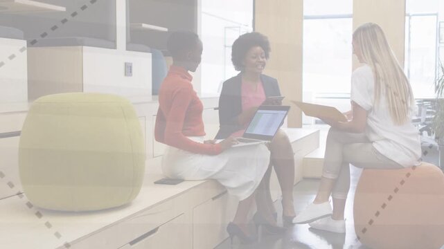 Right woman sliding folder, urging center woman using tab; charts rising over laptop for biz check
