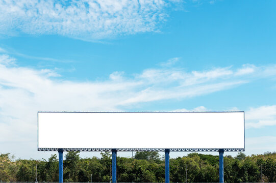 Wide, white empty billboard stands tall against a bright blue sky with light clouds. Perfect for advertising placement mockups, marketing displays, and outdoor brand promotion.