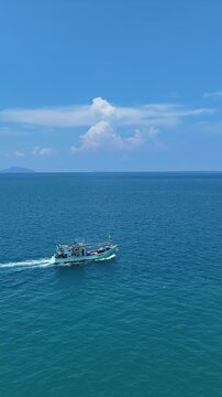 Sailboat Glides Peacefully on Vast Blue Sea with Distant Island and Hills Under Clear Sky, Evoking Tranquility on Ocean Horizon	