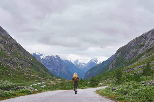 Mountain, backpacking and woman on road for journey, mockup space and fresh air on adventure or travel. Outdoor, person and hiking on weekend, exploration and trekking with view of valley and scenery