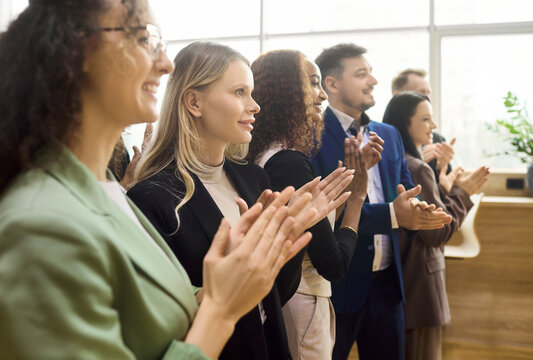 Business team professionals applauding success during meeting. Diverse colleagues smile and offer applause. Ideal for corporate training and celebration. Clear concept of teamwork and motivation.