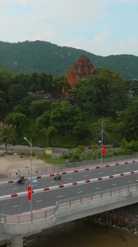 Nha Trang, Vietnam - The Po Nagar Cham Towers, a historic landmark, are seen from a bridge overlooking the city and a river. Traffic flows on the bridge, with buses and cars.