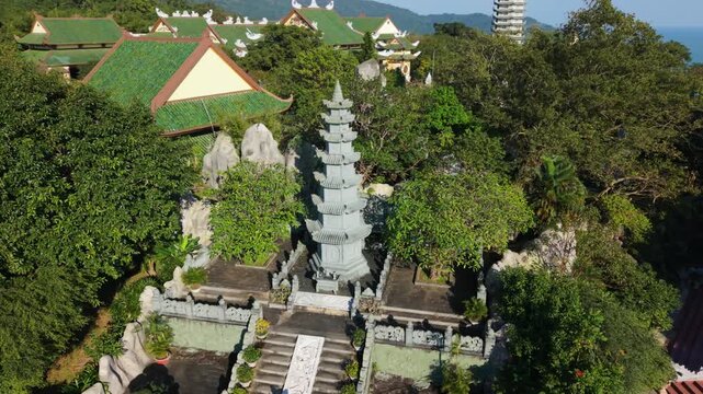 Vietnam, Da Nang Central Pagoda With Stair Approach Da Nang Vertical Stone Tower Set Before Stepped Entrance, Flanked By Sculpted Rocks And Lush Trees With Temple Roofs And Sea Beyond, Warm