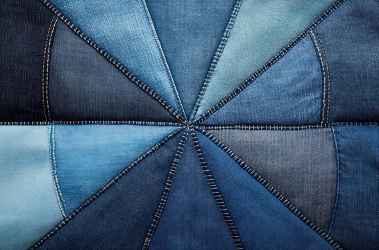 radial patchwork of triangular denim panels stitched into a starburst wheel with visible seams and varied blue tones, textured fabric evoking a cozy, handcrafted rustic creativity