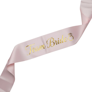Blush pink satin sash with elegant gold foil team bride calligraphy and a diamond ring icon on a neutral flat lay background wedding celebration atmosphere