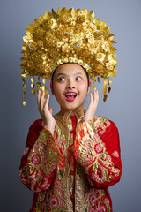 Naklejka premium Young Indonesian Asian Girl Wearing Ornate Gold Chinese Headdress And Embroidered Red Traditional Costume