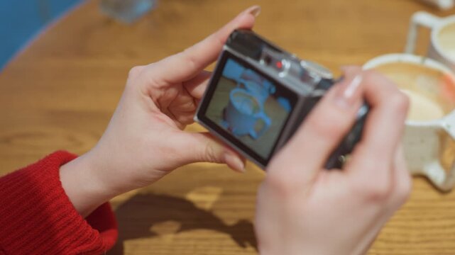 Individual checks composition on camera display. Person carefully reviews latte photograph on device screen. Content producer scrutinizes latte image closely displayed on camera monitor