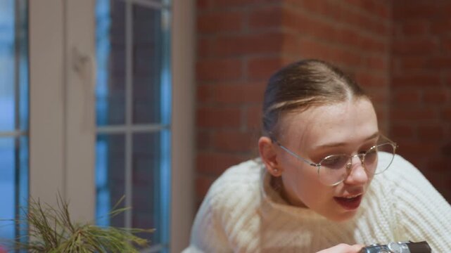 White woman in cafe passing camera to friend, cozy brick interior, soft window light, chunky sweater, vintage compact camera exchanged, hands framing shot, playful laughter, student photographer vibe,