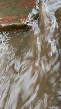 Close Up of Dirty Brown Rainwater Flowing Rapidly Through a Concrete Drainage System