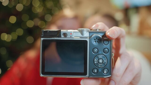 Friends checking camera photo cafe, two friends review captured selfie on compact camera screen amid warm bokeh lights, cozy table setting, candid laughter, hands holding camera, blurred background,