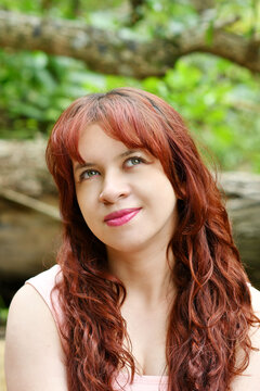 Mujer latina bonita con la mirada hacia arriba, cabello casta&ntilde;o y blusa rosada, retrato de una chica bella al aire libre. Toma Vertical.