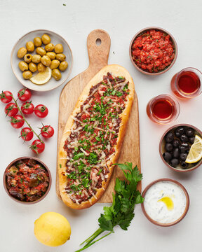 Turkish pide with minced meat, cheese and parsley with traditional meze, olives