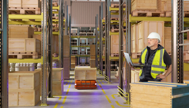Warehouse automation, Logistics operations. Supervisor monitors autonomous mobile robot moving wooden crate through storage racks with laptop