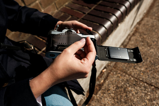 Photographer's hands loading 35mm film into vintage camera