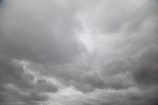Brooding cloudy sky looming over coast, churning cloudbanks, winddriven texture, restless sea suggested below, dramatic prestorm energy, strong contrast for editorial usage