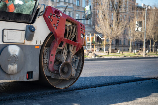 Roller for laying fresh hot asphalt on the road, city street. Closeup of road construction equipment. 