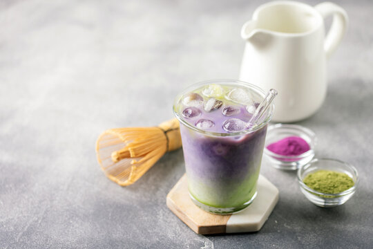 Ube tea is poured in iced matcha milk. Healthy vegan drink Ube Matcha Latte