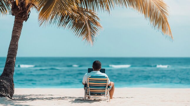 Man sits in striped beach chair, looking out at ocean from under shade of palm tree. High quality photo