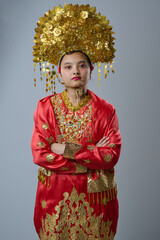 Naklejka premium Young Indonesian Asian Woman Wearing Ornate Gold Headdress and Red Traditional Costume Portrait