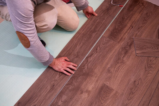  A worker installs laminate or quartz vinyl tile flooring