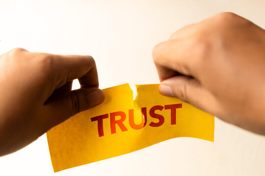 Hands tearing paper with word trust, broken relationship concept, trust issues