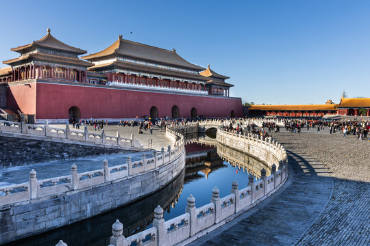 View of China Forbidden City South gate compound, canal during sunrise with distant and blurry unrecognizable tourists crowd