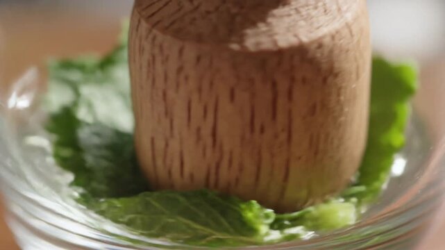 Muddling Fresh Mint Leaves with Wooden Pestle in Glass for Cocktail