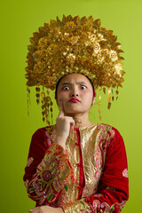 Naklejka premium Portrait Of A Young Indonesian Asian Girl Wearing A Golden Headdress And Traditional Red Costume With Playful Expression