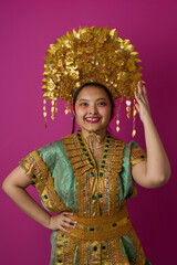 Naklejka premium Smiling Indonesian Asian Woman Wearing Ornate Gold Headdress And Traditional Embroidered Costume For Cultural Festival