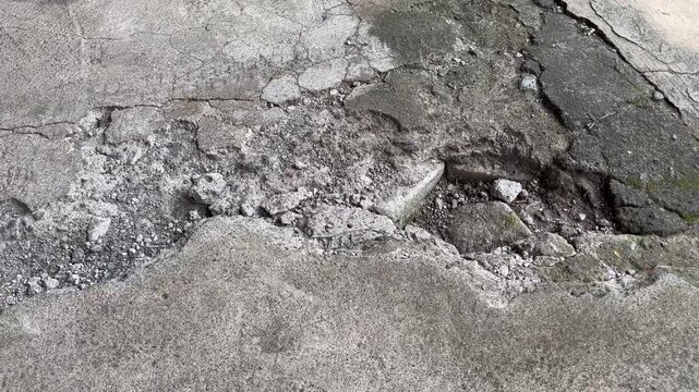 Severely Damaged and Broken Concrete Pavement with Potholes